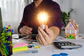 Energy Resource Center Person holding illuminated lightbulb sitting at a desk with a calculator and other office supplies strewn about
